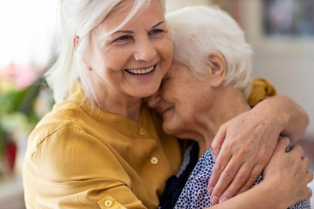two senior women happily embrace