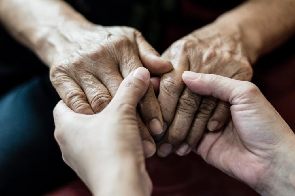 someone holds the hands of an elderly loved one who has just received an alzheimer's diagnosis