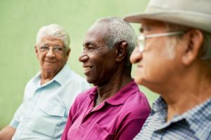 three happy senior men socialize around their assisted living facility regularly