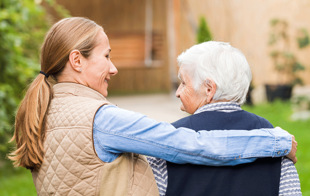 Woman wraps arm around senior with dementia