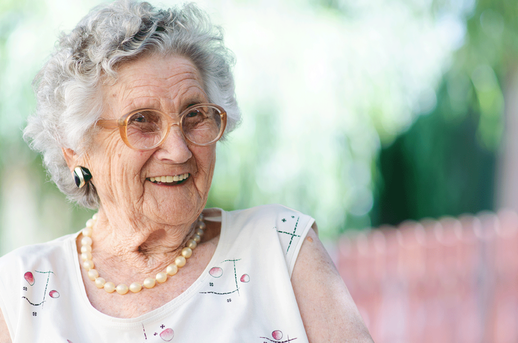 Senior sits in senior independent living facility, smiling