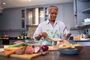 Woman cooks in kitchen, after learning about the challenges of independent living