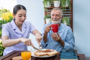Senior enjoys meal with health worker as he enjoys benefits of assisted living facilities