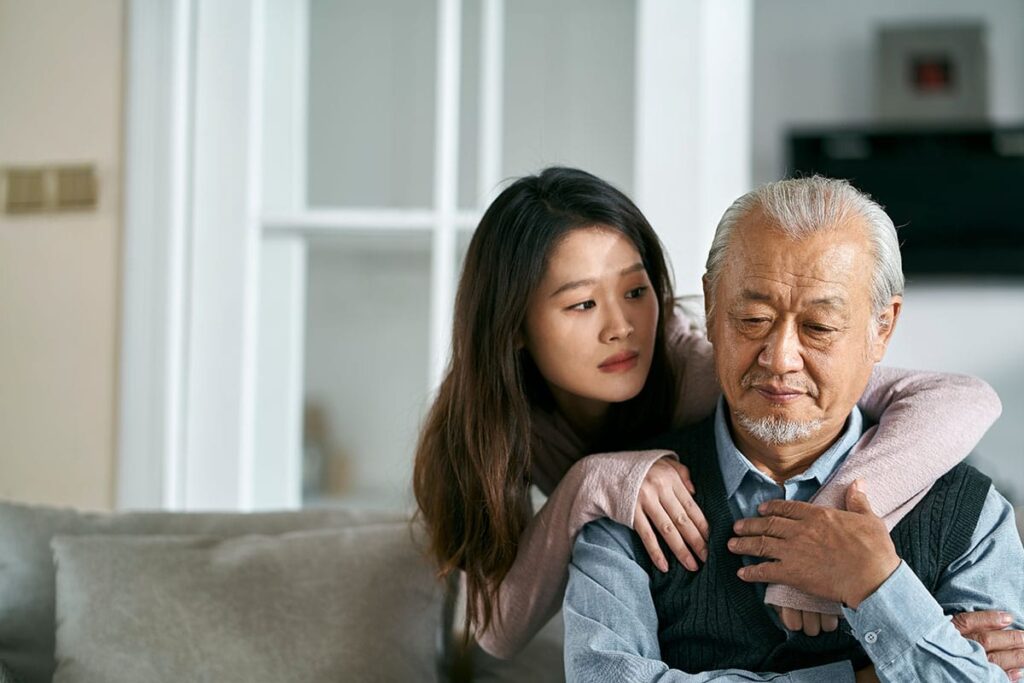 Woman puts her arms around her father, wondering if he needs an alzheimer's care program