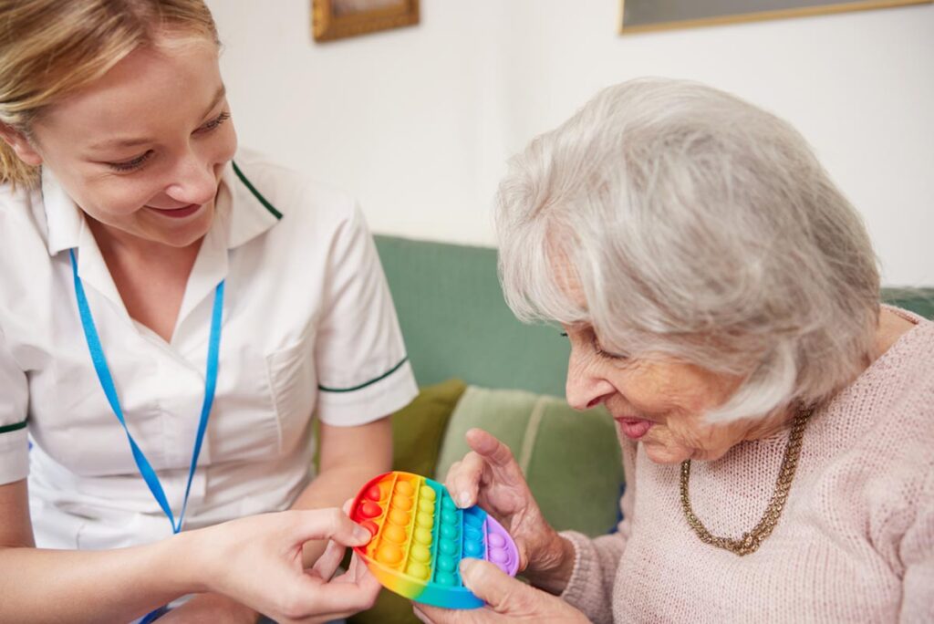 Senior plays with toy as nurse comes up with memory care activity ideas