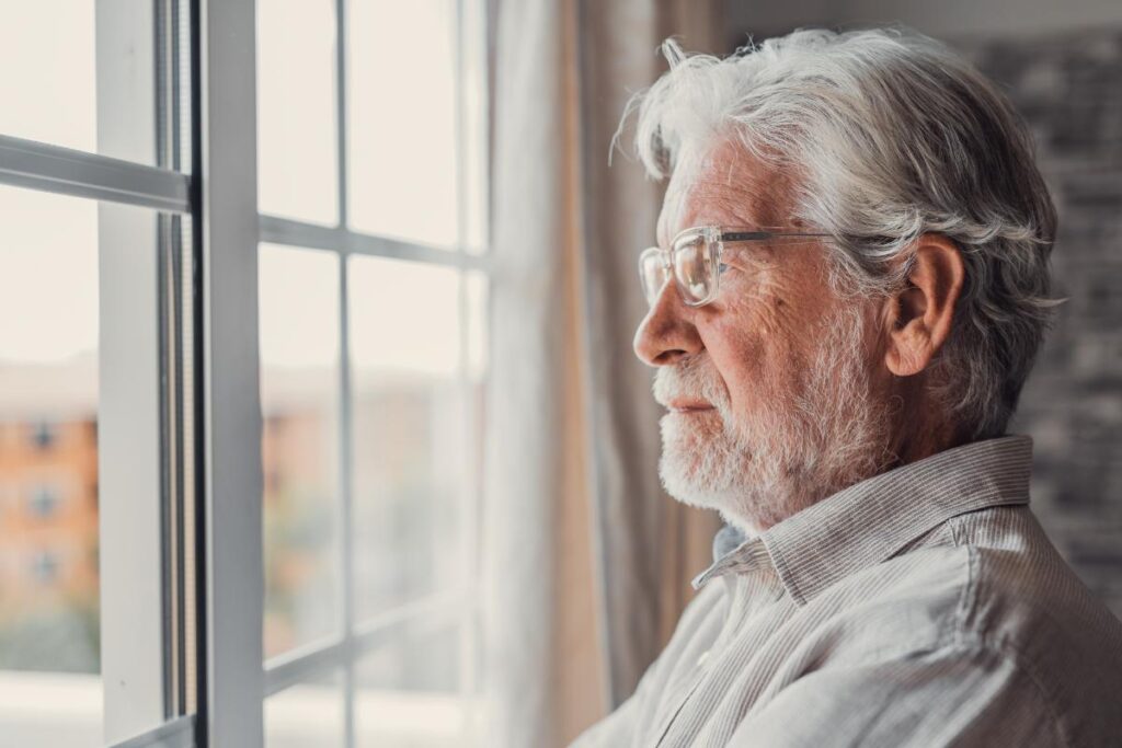 Senior looks out window and ponders when it is time for assisted living