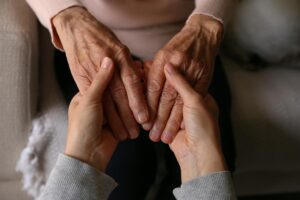 Nurse holds hands with senior while talking to her about long-term skilled nursing care benefits