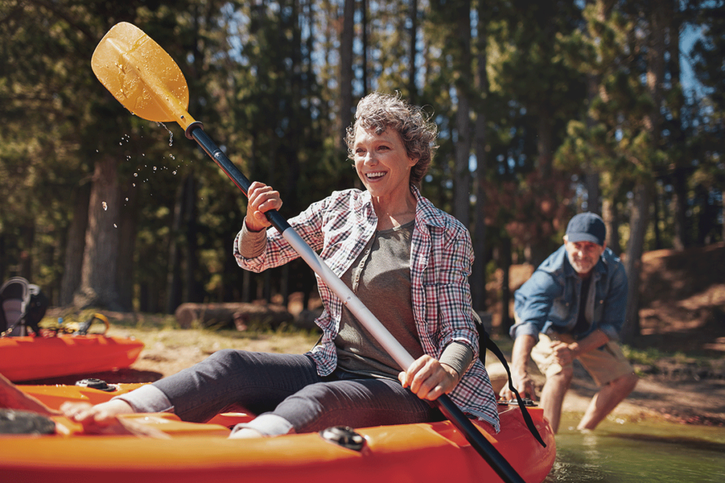 a senior kayaks through a beautiful lake to show staying active as a senior