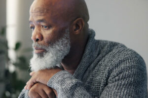 Man looks out window as daughter researches how to support seniors with depression and anxiety